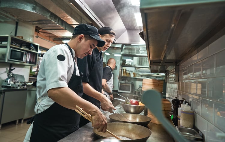 two-chef-assistants-cooking-new-dish-restaurant-kitchen